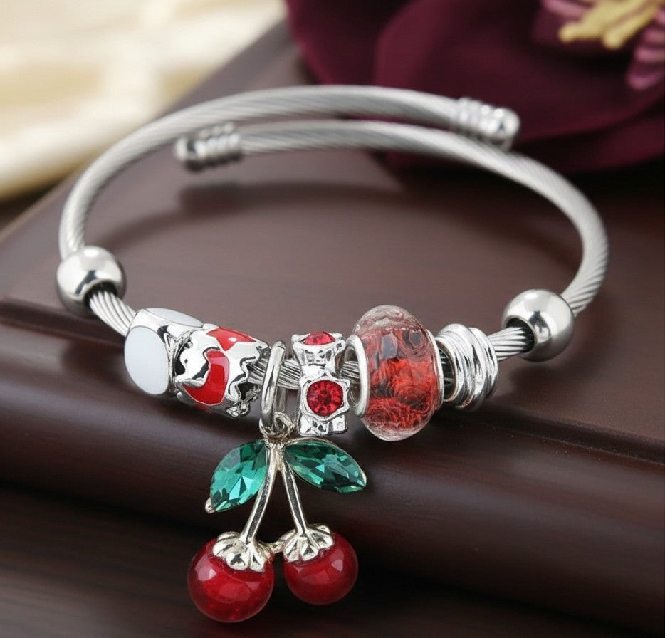 House of eLLe silver charm bracelet featuring a red cherry pendant with green crystal leaves and red glass beads.