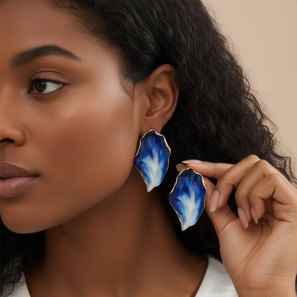 House of eLLe Beautiful Me earrings featuring organic, gradient blue resin shapes with gold-tone edges on a model.