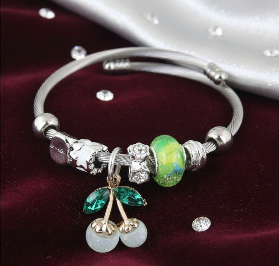 House of eLLe Cherries On Top bracelet featuring a silver cable band, green cherry charm, and decorative glass beads.