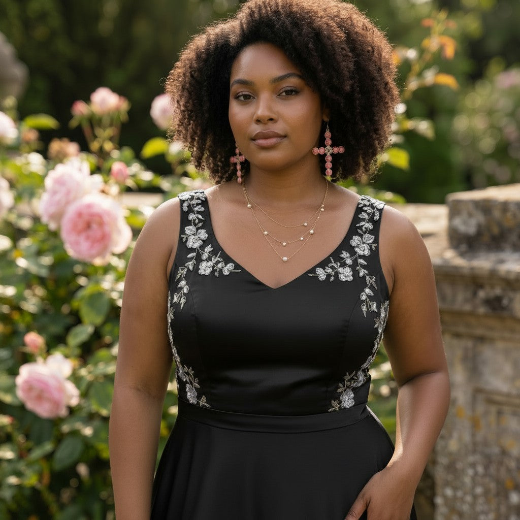 House of eLLe light pink bling cross earrings worn by a woman in a black floral dress in a garden setting.
