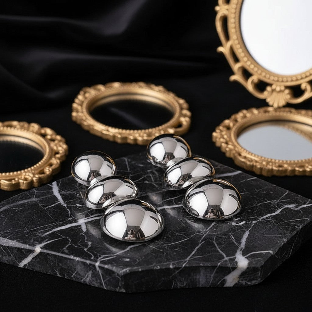 House of eLLe I'm Flexible silver dome earrings displayed on a black marble slab with ornate gold mirrors.