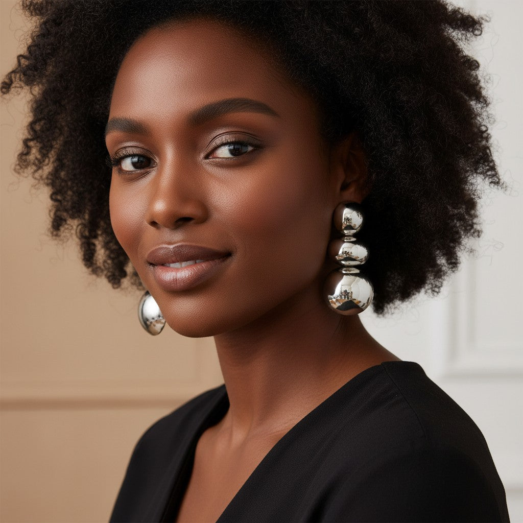 Model wearing House of eLLe I'm Flexible silver drop earrings featuring three graduated polished metallic spheres.