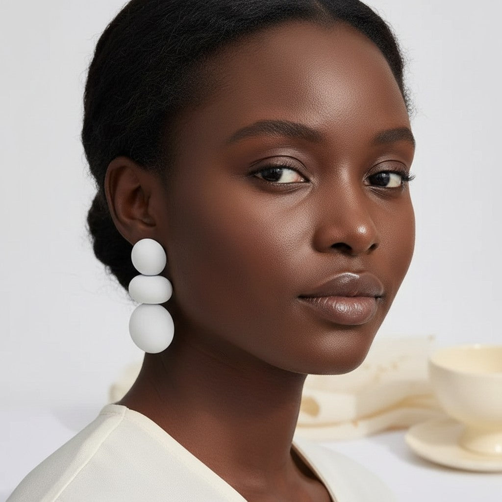 Model wearing House of eLLe I'm Flexible white statement earrings featuring three stacked smooth matte spheres.