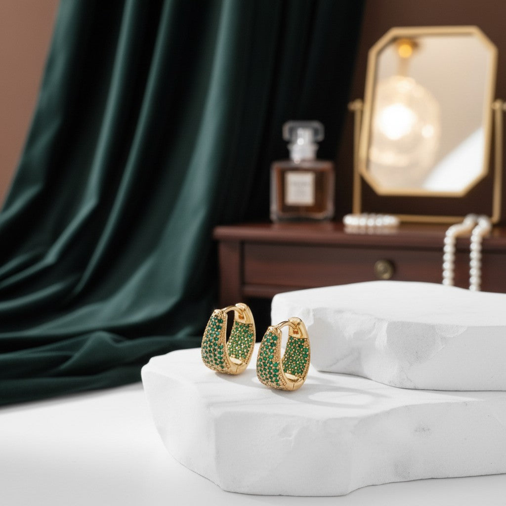 House of eLLe Dipped In Bling gold hoop earrings featuring vibrant green pavé diamonds on a white stone display.