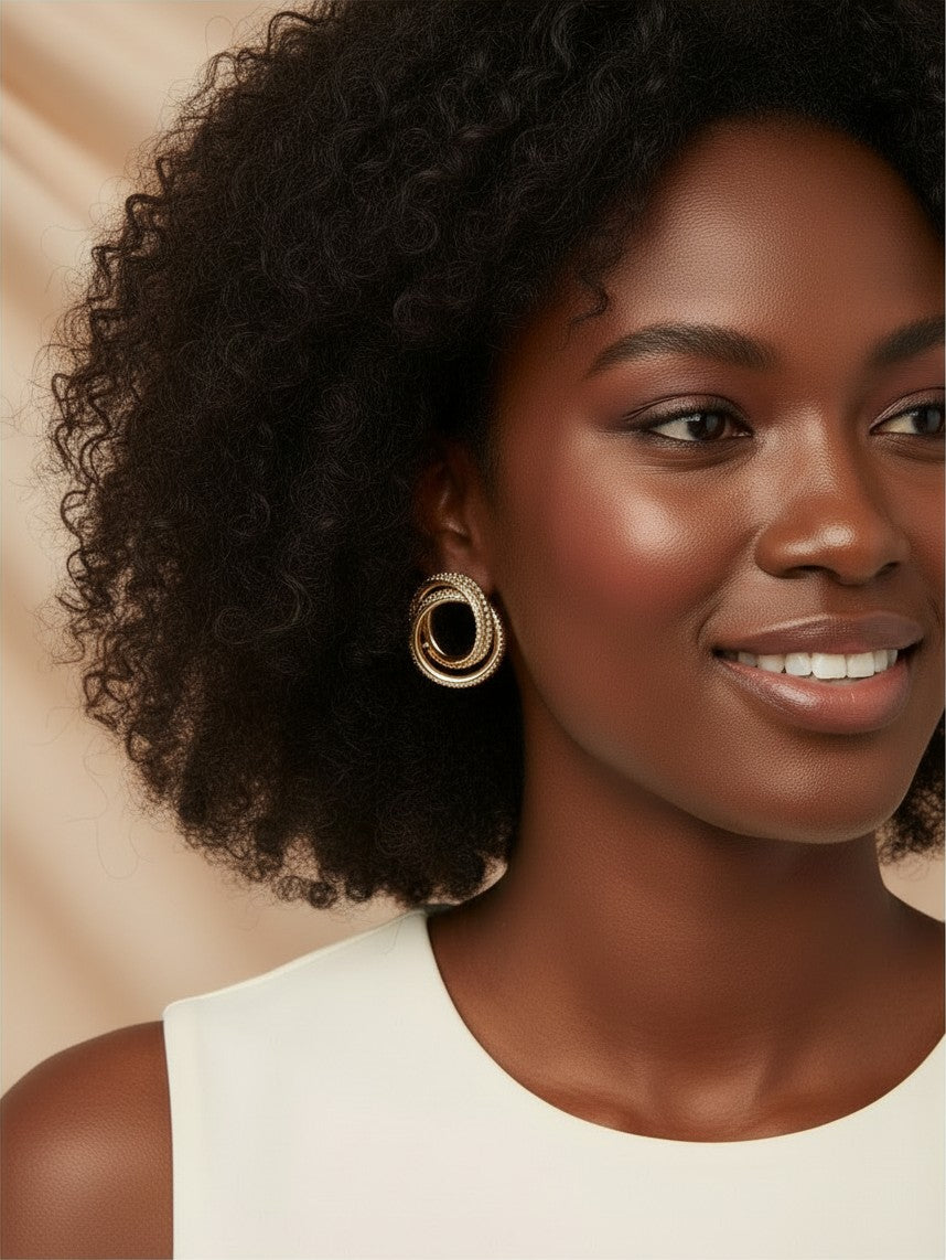 House of eLLe Sass In The City gold hoop earrings worn by a smiling woman with curly hair