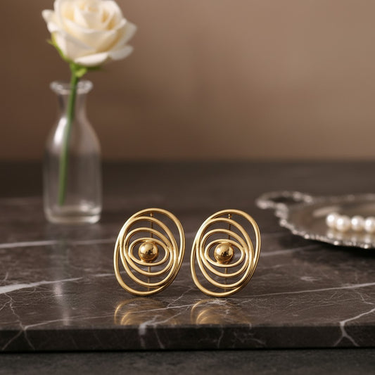 House of eLLe gold earrings featuring a modern concentric oval design with a central polished sphere on marble
