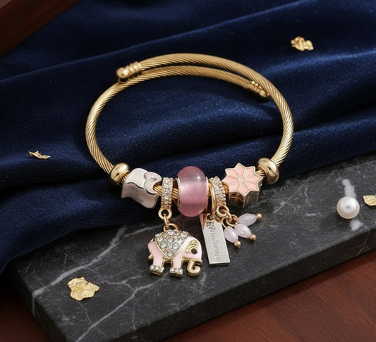 House of eLLe gold-tone cable bracelet featuring a pink enamel elephant charm with crystals and floral accents.