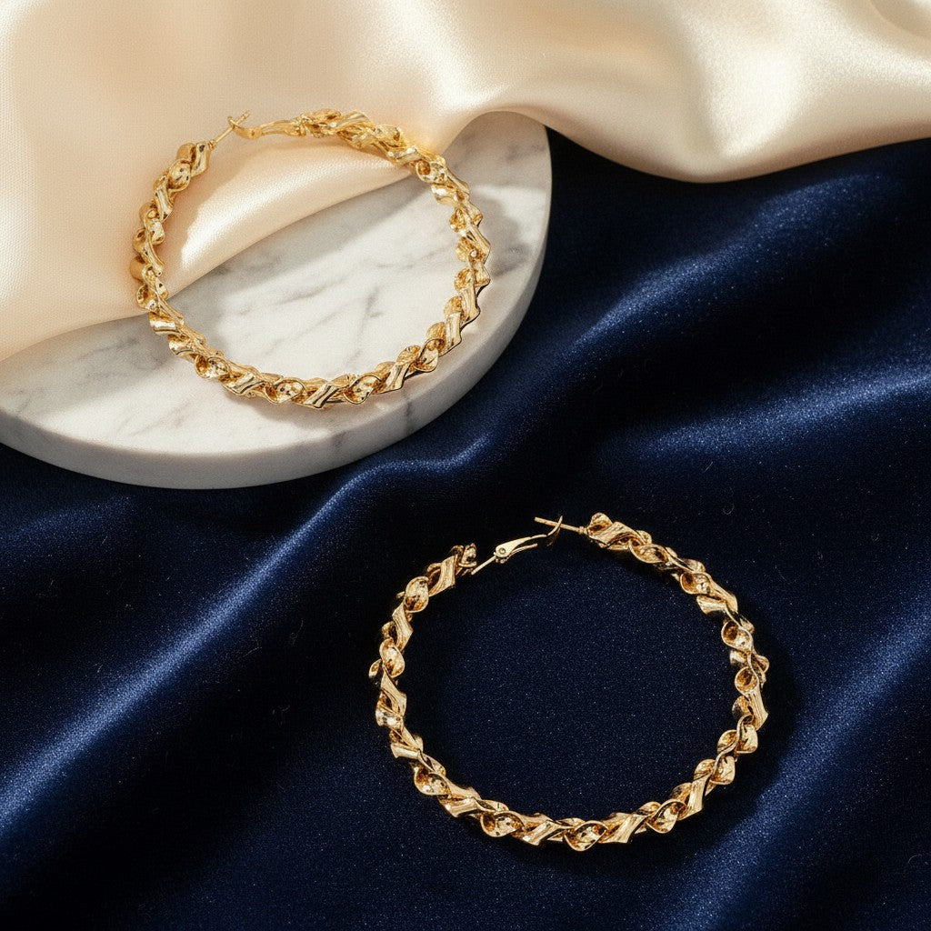 House of eLLe My Twisted Hoops in gold, featuring a textured, spiraled design on a marble and velvet background.