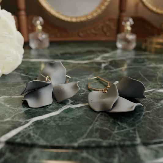 House of eLLe gray acrylic drop earrings featuring a delicate floral petal design on a green marble vanity surface.