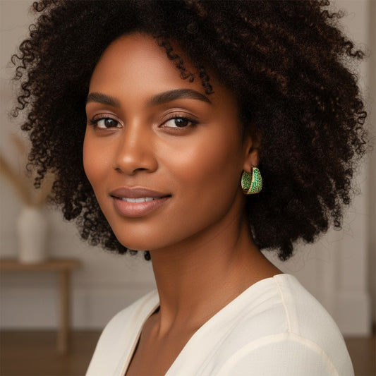 House of eLLe Dipped In Bling hoop earrings featuring green pavé diamonds on a woman with curly hair.