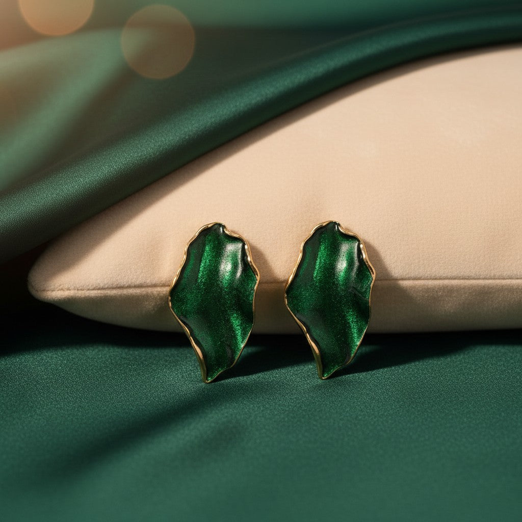 House of eLLe Beautiful Me earrings featuring organic leaf-shaped green enamel with gold trim on a satin background