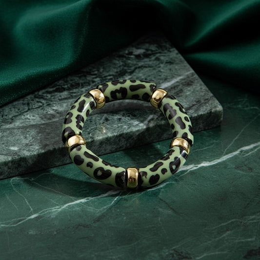 House of eLLe mint green and black leopard print bangle bracelet with gold-tone accents on a green marble surface