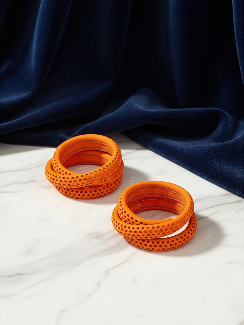 House of eLLe Sass In The City orange hoop earrings with a perforated texture on a marble surface