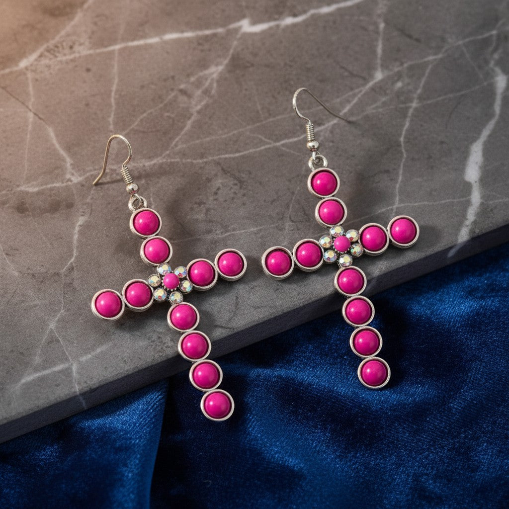 House of eLLe dark pink cross earrings with silver-tone metal and sparkling rhinestone accents on a velvet surface.