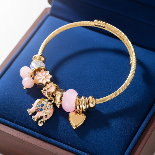 House of eLLe gold-tone stainless steel bracelet featuring pink elephant, heart, and flower charms in a blue box.