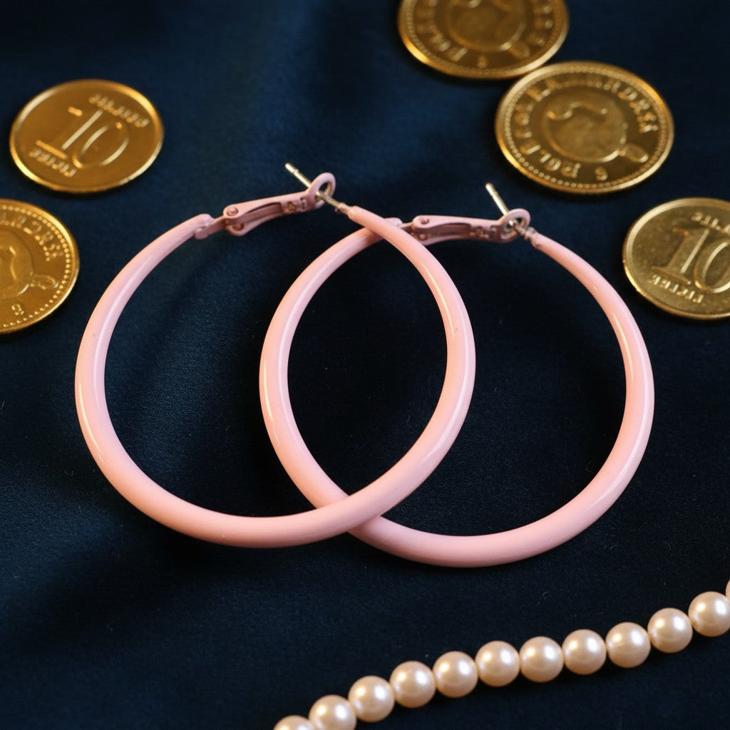 House of eLLe Springtime hoop earrings in pastel pink, featuring a smooth finish on a dark blue fabric background.