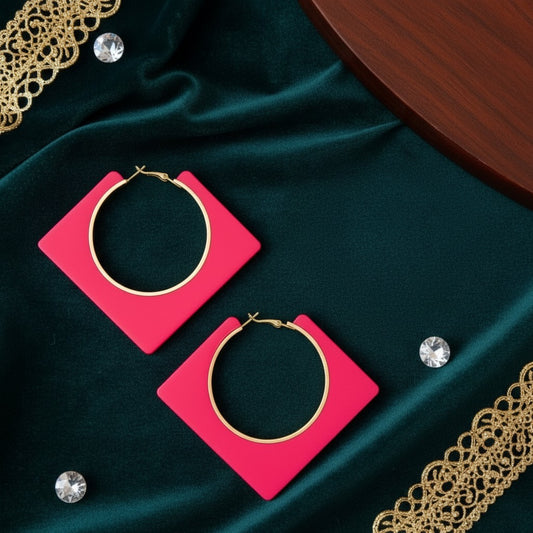 House of eLLe pink square hoop earrings with gold-tone circular centers on a dark green velvet background.