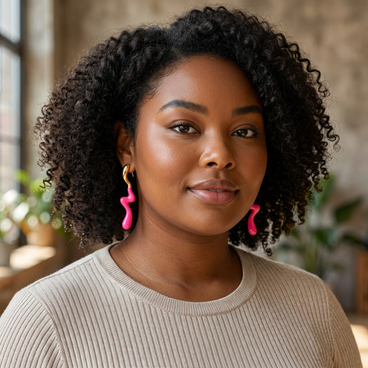 A woman wearing House of eLLe Dripped In Glam pink stainless-steel earrings with a unique wavy, melted design.