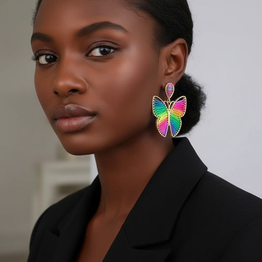 Model wearing House of eLLe rainbow butterfly earrings with vibrant thread detail and gold-tone metal frames.