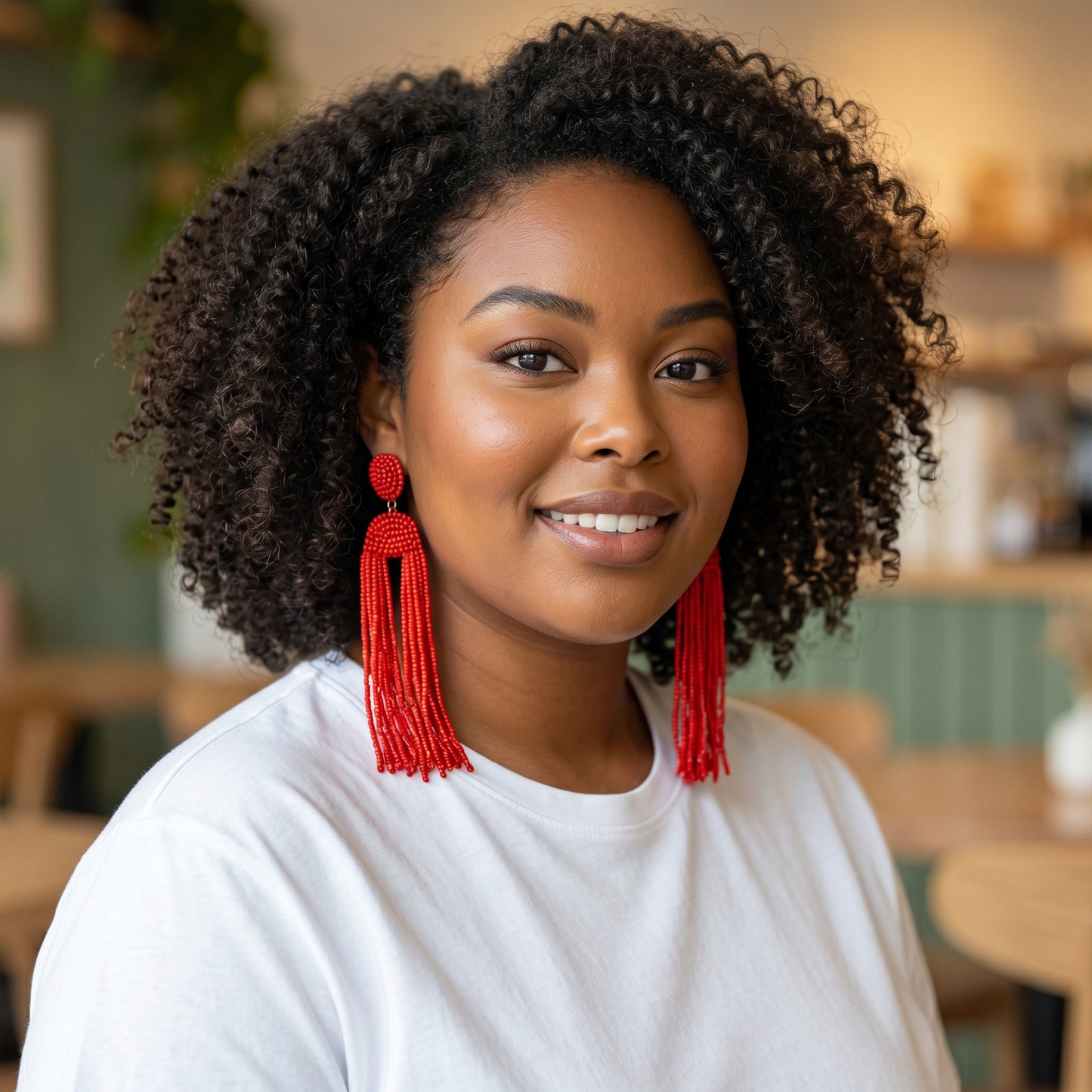 Woman wearing House of eLLe Queen Era red beaded fringe statement earrings with a white t-shirt