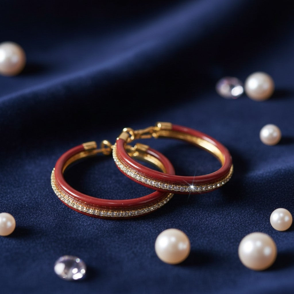 House of eLLe red enamel double hoop earrings with sparkling crystal accents on a navy blue velvet background.