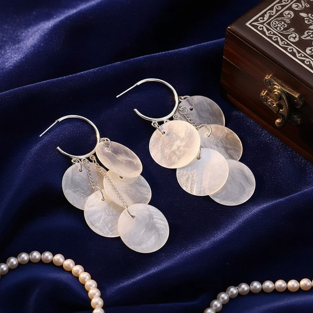 House of eLLe Shell Life earrings featuring iridescent mother-of-pearl disc charms on silver hoops.