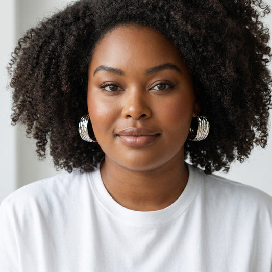 Model wearing House of eLLe Larger Than Life silver hoop earrings with a textured finish and white t-shirt.