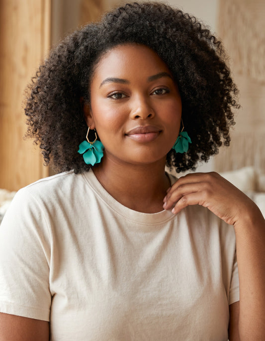 Model wearing House of eLLe Mini Falling For You turquoise acrylic petal drop earrings with gold geometric accents.