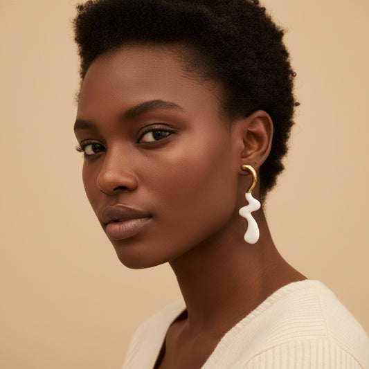 Model wearing House of eLLe Dripped In Glam white and gold stainless-steel abstract drop earrings