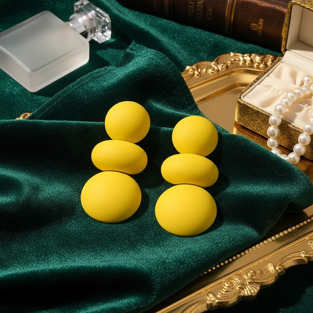 House of eLLe I'm Flexible yellow statement earrings with stacked matte circular beads on green velvet fabric.
