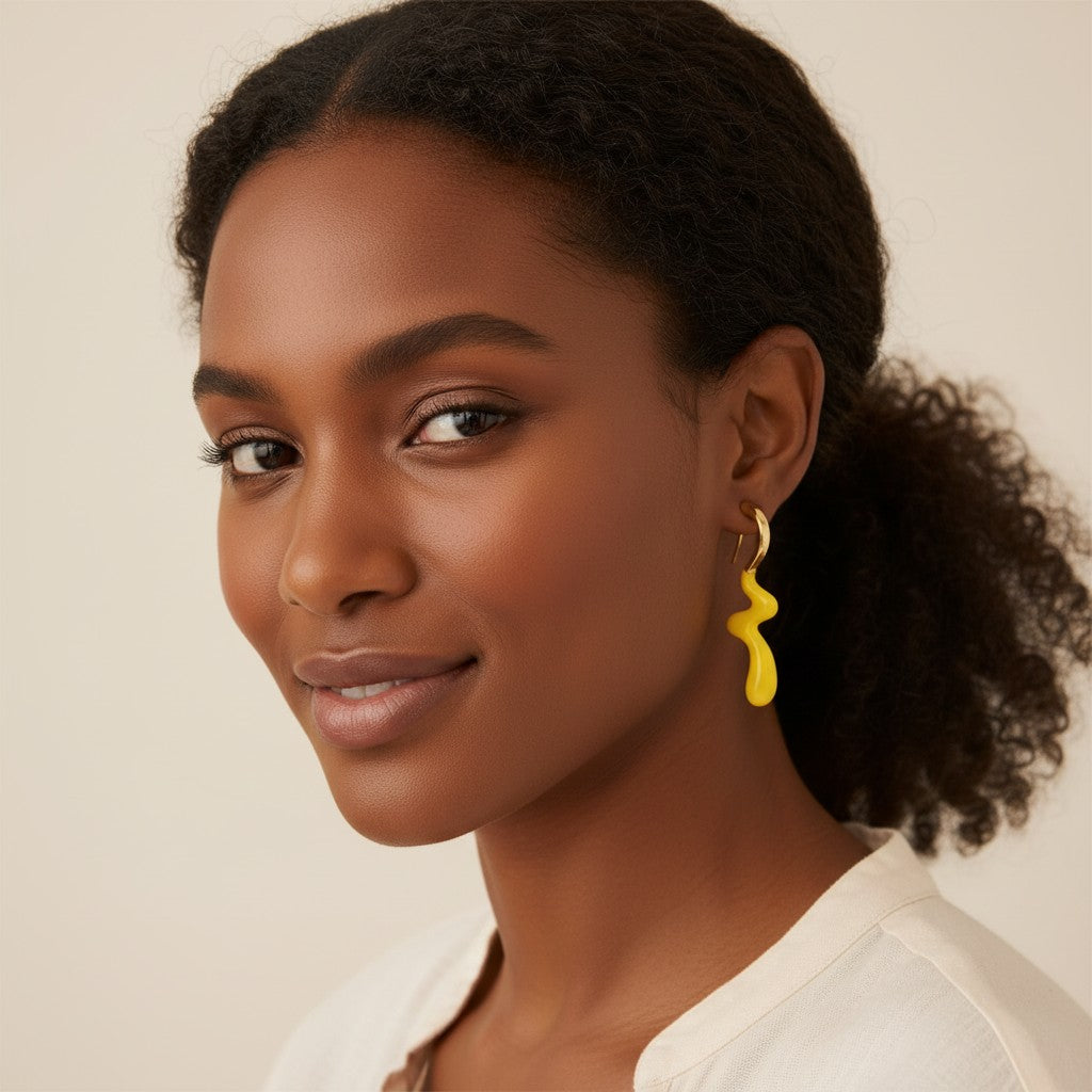 Model wearing House of eLLe Dripped In Glam yellow stainless-steel earrings with a unique wavy, liquid-like design.
